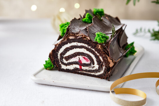 Buche de Noel. Traditional Christmas dessert, Christmas yule log cake with chocolate cream. Christmas tree branches.