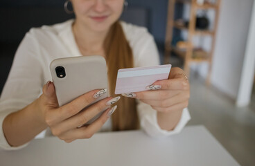 Young girl holding a mobile phone and a credit card in her hands