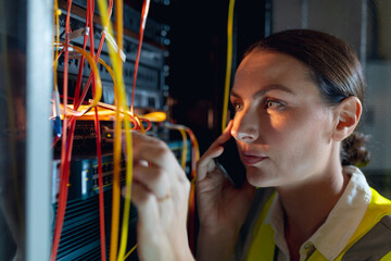 Close up of caucasian female engineer talking on smartphone while inspecting in computer server room - Powered by Adobe