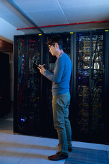 Asian male engineer writing on clipboard in computer server room