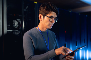 Asian male engineer using digital tablet in computer server room