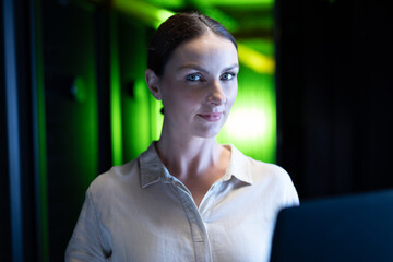 Portrait of caucasian female engineer with laptop in computer server room