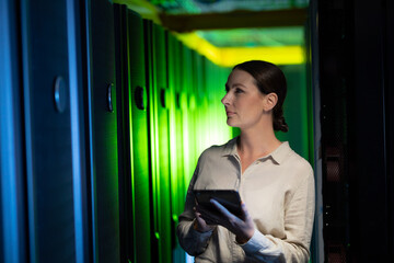 Caucasian female engineer using digital tablet while inspecting in computer server room
