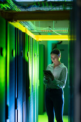 Caucasian female engineer using digital tablet while inspecting in computer server room