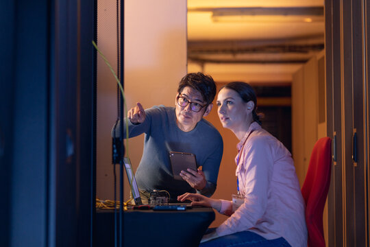 Diverse male and female engineers discussing over a digital tablet while inspecting in server room