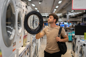 Male shopper looking inside washing machine