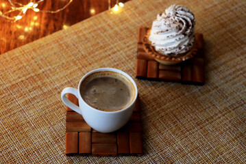 a cup of coffee and tartlet whipped cream sprinkled with cocoa