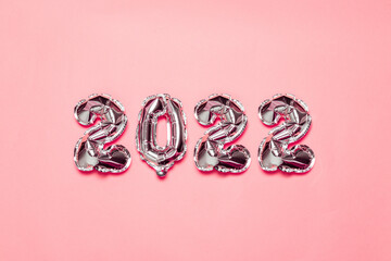 Obraz na płótnie Canvas 2022 silver foil balloons decor and snow with copy space on pink background. New Year concept. Christmas Eve