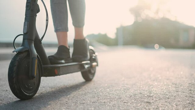 electric scooter. child riding electric a scooter close-up sun glare. road transport in city concept. speed sport energy concept. wheel close-up drive bicycle. eco sun future