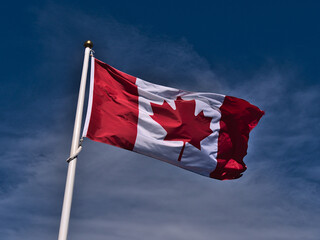 Low angle view of flying Canadian national flag with white and red colors and maple leaf in center...