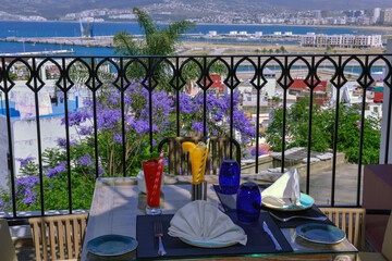 Fototapeta na wymiar Table with orange juice and the Moroccan port of Toja in the background. travel concept