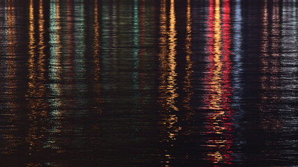 Stunning night view of the calm water surface of Burrard Inlet viewed from North Vancouver, British Columbia, Canada with colorful reflections.