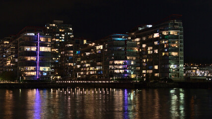 Fototapeta na wymiar Beautiful night view of illuminated modern apartment buildings on the shore of Vancouver North, British Columbia, Canada near The Shipyards.