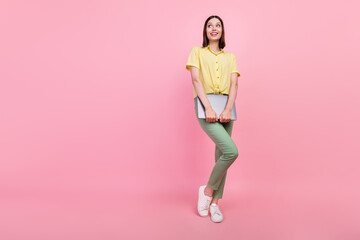Full body photo of young girl happy positive smile hold laptop dream curious look empty space isolated over pink color background