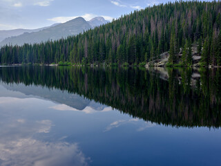 Pine trees and mountains reflected in the calm waters of Bear lake in Rocky Mountain National Park Colorado