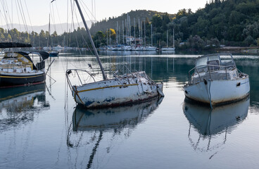 Broken derelict sailing boats in shallow waters.