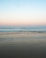 Minimalist moving ocean waves on sandy beach at sunset