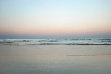 Fototapeta na wymiar Minimalist moving ocean waves on sandy beach at sunset