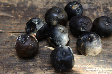 Rotten apples lit by the sun on a wooden board