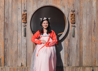happy Asian woman tourist in red Hanfu ancient Chinese traditional ethnic costume sit in front of wooden window 