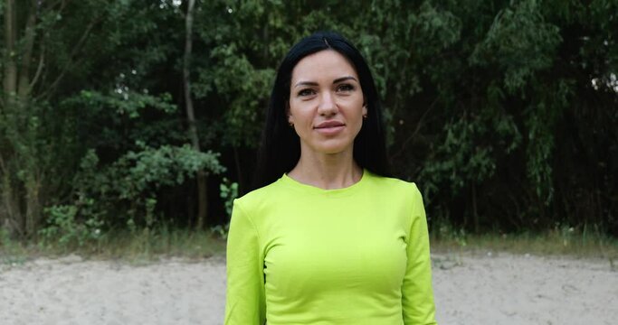 Young woman with long black hair in a light green sweater near the forest in nature