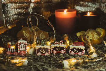 Christmas still life with a gingerbread train, a garland in the form of jars with a Christmas tree and snow. The still life is located on a knitted scarf, which gives the photo an atmosphere