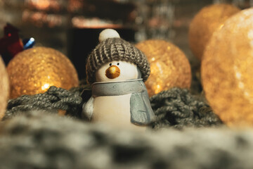 Christmas still life with a ceramic figurine of a penguin in a knitted hat, a garland in the form of balls woven from threads. The still life is located on a knitted scarf