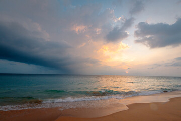 Fototapeta na wymiar Ocean waves on the sandy beach under a gorgeous sunset sky with clouds on Sri Lanka island.