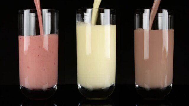Verschiedene Michshakes - Michshake mit Erdbeere, Vanille und Kakao auf schwarzem Hintergrund