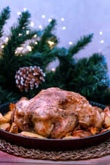 Christmas chicken baked with potatoes, herbs, with the decoration of the set table. Christmas dinner, a festive dish. Side view of the table, close-up. Selective focus