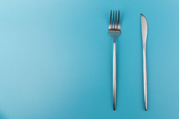 A fork and knife on blue background. Flat lay Dishes for breakfast, lunch or dinner.