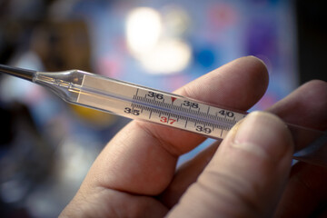 High temperature on the thermometer. 37 degrees on the thermometer. Thermometer in a man's hand....