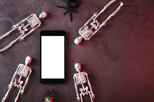 Decorative skeletons lie near the smartphone on a dark background.