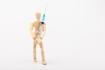 wooden mannequin with syringe against white background