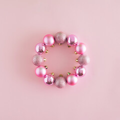 A creative Christmas arrangement made of baubles in the shape of a circle on a pastel pink background. Minimal New Year concept. Frame with copy space inspiration.