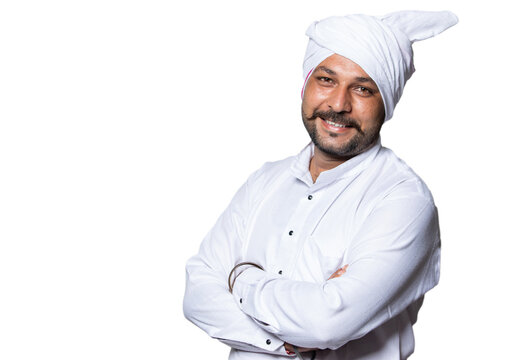 Young happy Indian village mustache man wearing kurta and turban standing over isolated white studio background posing with arms crossed, smiling healthy rural male looking at camera satisfied.