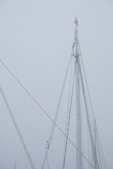 Fototapeta premium Sailboat masts in heavy fog in a safe protected harbor.