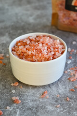 Fototapeta na wymiar Pink Himalayan rock salt coarse in a white bowl on gray background