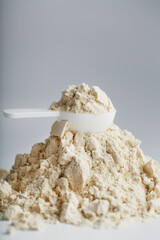 A pile of protein powder with a measuring spoon on a white background.
