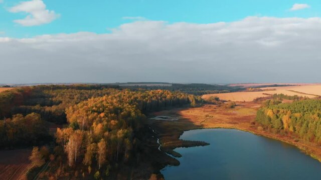 Aerial view of lake at sunrise in autumn. Meadows, orange grass, trees. Colorful landscape of river sunset. Horodok Ukraine