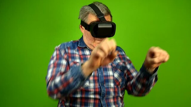 Mature adult man using virtual reality glasses simulates riding horse in virtual game. Green screen.