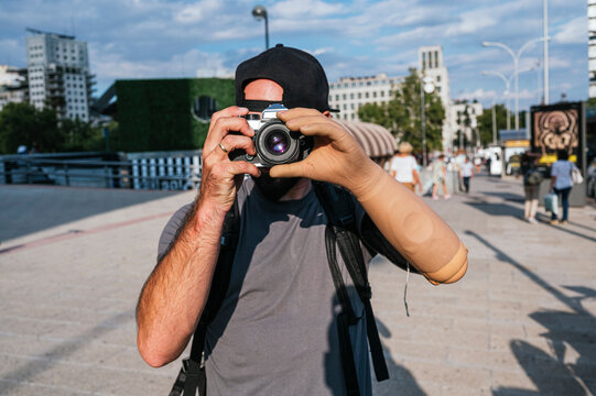 Man with artificial arm taking photo in city