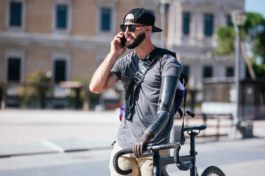 Smiling man with prosthetic arm talking on smartphone