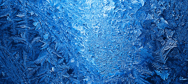 Winter Frosty Blue Patterns on the Glass. Icy, Frosty Pattern on the Window Glass. Background for Christmas and New Year. Macro Close Up