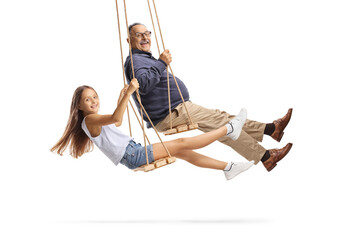 Side shot of a grandfather and granddaughter swinging on wooden swings