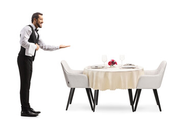 Full length profile shot of an elegant waiter welcoming next to a restaurant table