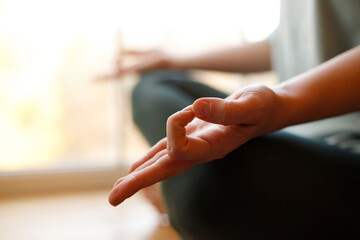 Close-up of woman's hand during meditation sitting on windowsill. Mental healthcare concept.