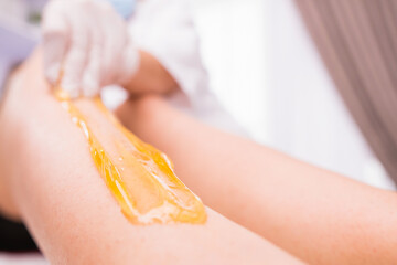 Cropped photo of waxing epilation procedure for removing hair with sugaring paste in the beauty salon, spa center beauty and body care concept.