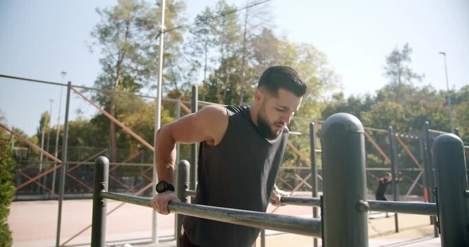 The guy warms up, stretches his muscles,and then does exercises on parallel bars
