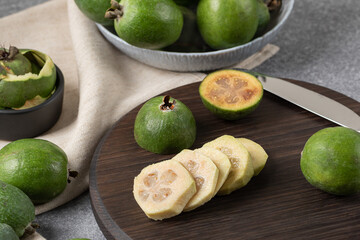 slices and different sized pieces of chopped feijoa on dark backboard. Vitamin juice preparation...